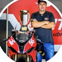 Paulo Defavari, fundador da Sport Plus Racing, com troféu ao lado de uma moto de corrida